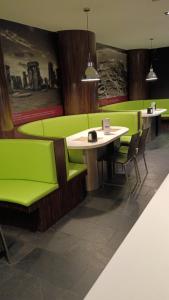a restaurant with green booths and a table and chairs at km24 ALBERGUE in Padrón