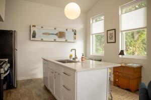 a kitchen with white cabinets and a sink and two windows at Blue Crest Architectural Treehouse Retreat in Ocean Springs