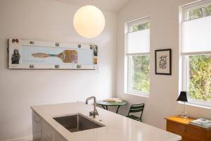 a white kitchen with a sink and a table at Blue Crest Architectural Treehouse Retreat in Ocean Springs +52 photos