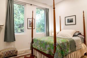 a bedroom with a four poster bed and two windows at Blue Crest Architectural Treehouse Retreat in Ocean Springs