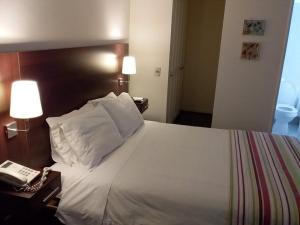 a bedroom with a white bed with two lamps and a phone at Alojarte SAI in Estación El Salto