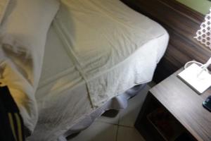 a bed with a white pillow and a night stand at Alojarte SAI in Estación El Salto