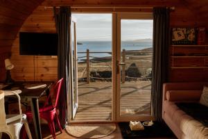 a room with a door to a balcony with a view of the ocean at The Sleepy Crofter Glamping - Achiltibuie in Achiltibuie