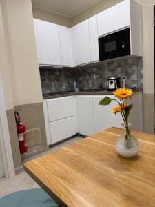 a vase of flowers on a wooden table in a kitchen at Maison ì room, suite & apartment in Reggio di Calabria