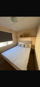 a large bed in a small room with a window at J&A Caravan in Rhyl