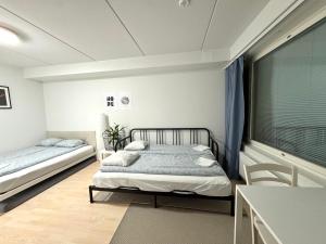 a bedroom with two beds and a table and a window at Easy Stay Rooms & Apartments near Airport in Vantaa