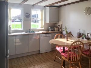 a kitchen with white cabinets and a table and chairs at Murton Farm Cottage in Horton +3 photos