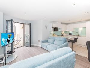 a living room with a blue couch and a kitchen at Apartment 19 in Newquay