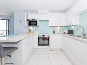 a white kitchen with white cabinets and appliances at Apartment 19 in Newquay +21 photos