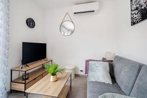 a living room with a couch and a flat screen tv at la pause detente, villa climatisée avec jardin et parking privés, à 5 mn de la mer, au calme in Martigues