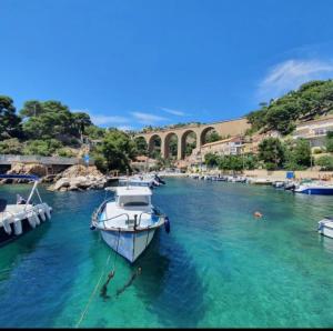 a boat docked in a river with a bridge in the background at la pause detente, villa climatisée avec jardin et parking privés, à 5 mn de la mer, au calme in Martigues