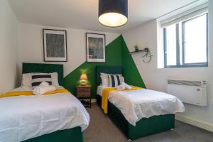two beds in a room with green and white at Vantage Stays in Gloucester