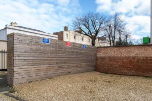 a brick fence with blue and red signs on it at Vantage Stays in Gloucester