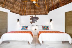 two beds in a white room with a ceiling at Mahekal Beach Front Resort & Spa in Playa del Carmen