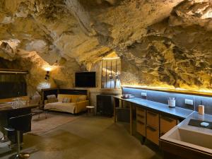 a kitchen and living room with a rock wall at La Grotte du Moulin in Noyers-sur-Cher