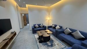 a living room with a blue couch and a tv at The Queen Apartment in Jeddah