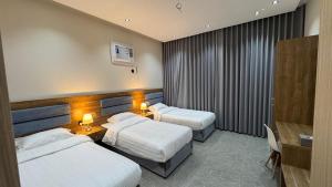 a hotel room with two beds and a desk at The Queen Apartment in Jeddah