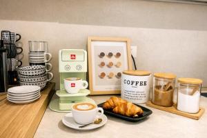 a counter with cups of coffee and a plate of croissants at Japandi Suites Olbia in Olbia