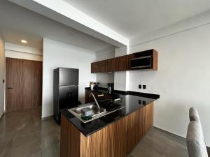 eine Küche mit schwarzer Arbeitsplatte und Kühlschrank in der Unterkunft Frente a la Playa con acceso directo AC Alberca y Elevador in Veracruz
