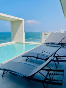 Ein Swimmingpool mit Liegestühlen und dem Meer im Hintergrund in der Unterkunft Frente a la Playa con acceso directo AC Alberca y Elevador in Veracruz