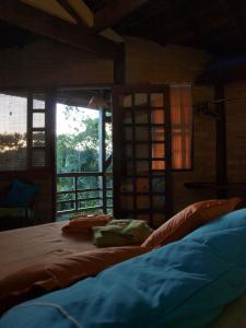 a bedroom with a bed and a large window at Pousada Casa Milà in Ubatuba