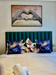 a bed with a green headboard with a heart picture at Chic studio with sea view, Wi-Fi & pool in Aïn Harrouda +29 photos