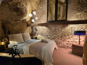 a bedroom with two beds and a stone wall at La Grotte du Moulin in Noyers-sur-Cher