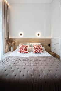 a bedroom with a large bed with red and white pillows at Porto Marina - widok na jezioro z każdego z 3 pokoi, lux, garaż, klima in Iława