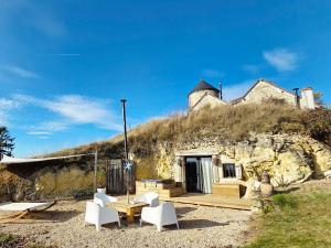 a house with a table and chairs in front of it at La Grotte du Moulin in Noyers-sur-Cher