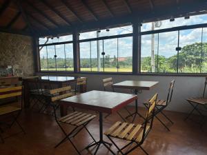 a dining room with tables and chairs and windows at Recanto do Sitio in Tiradentes