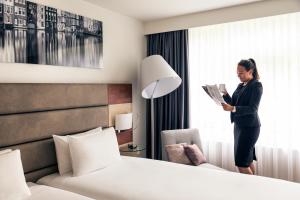 
a woman standing in front of a bed in a hotel room at Mercure Hotel Amsterdam West in Amsterdam
