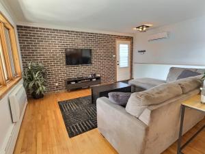 a living room with a couch and a brick wall at Sir'Eau d'Érable in St-Ferdinand