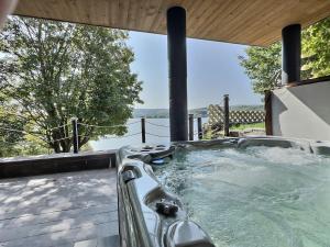 a hot tub on a deck with a view of the water at Sir'Eau d'Érable in St-Ferdinand