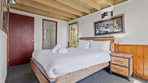 a bedroom with a large bed with white sheets at Eagles Nest in Mount Hotham