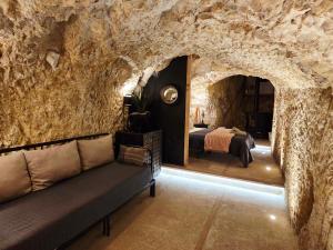 a room with a couch in a stone wall at Le Tunnel du Moulin in Noyers-sur-Cher