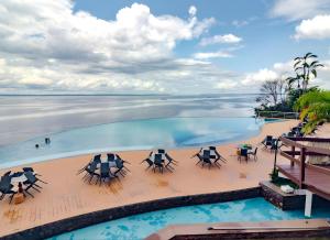 an infinity pool with tables and chairs and the ocean at Tropical Executive Hotel Flat 205 in Manaus