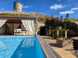 a house with a swimming pool and a building with a tower at Le Tunnel du Moulin in Noyers-sur-Cher