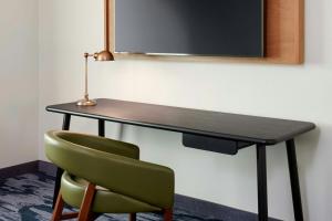 a desk with a green chair and a television at Fairfield by Marriott Inn & Suites Morrow in Morrow