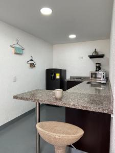 a kitchen with a counter with a microwave and a stool at Kaza Living Usaquén in Bogotá