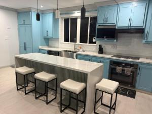 a kitchen with blue cabinets and a counter with stools at Mullins Bayfield Gardens House in Saint Peter