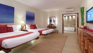 a hotel room with two beds and a flat screen tv at Bluewater Maribago Beach Resort in Mactan