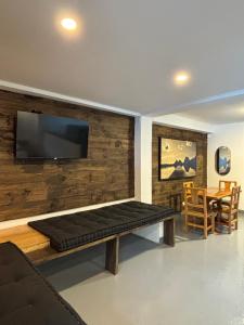 a living room with a bench and a flat screen tv at Kaza Living Usaquén in Bogotá