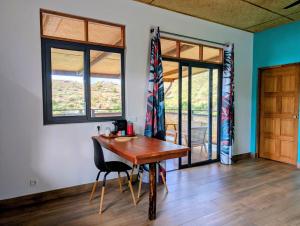 a dining room with a wooden table and two windows at ManaHenua Lodge in Nuku Hiva
