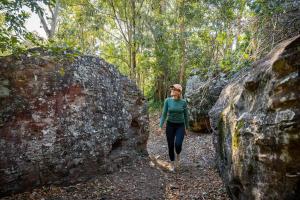 a woman walking through a forest between two large rocks at Stone Guest House Ebenezer in Ebenezer +9 photos