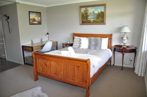 a bedroom with a wooden bed with white sheets at Parnwell Villa Apartment - The Tropical Oasis in Tauranga +39 photos