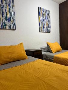 a hotel room with two beds with yellow sheets at Acogedor y céntrico Departamento in León