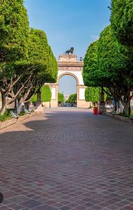 an arch in a park with trees and a brick road at Acogedor y céntrico Departamento in León