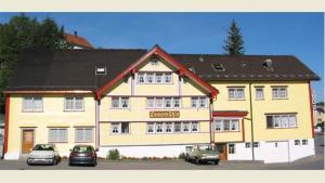 a large yellow building with cars parked in front of it at Loosmühle in Weissbad