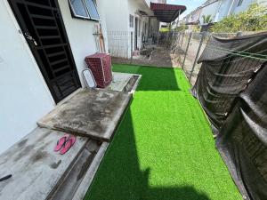 a porch with green grass and a door with pink flip flops at QQ UniStay in Pagoh