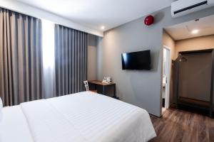 a bedroom with a white bed and a flat screen tv at Stay Kertapati Hotel in Kertapati